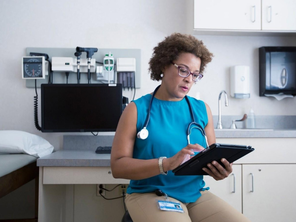 a female doctor sitting in an office holding a tablet